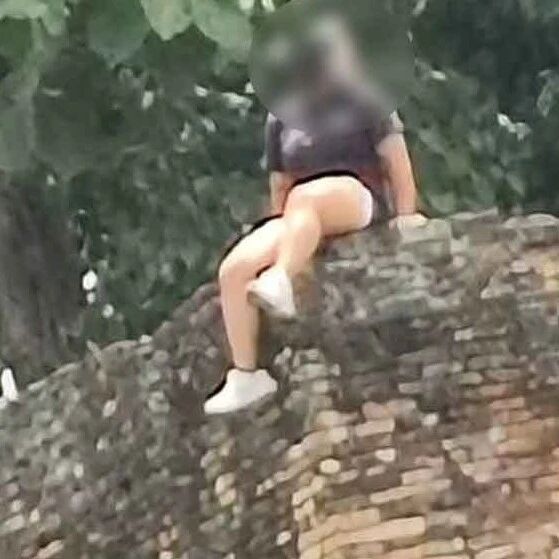 中国女游客爬上清迈古城墙拍照,双腿悬空!当地居民批评:行为不妥